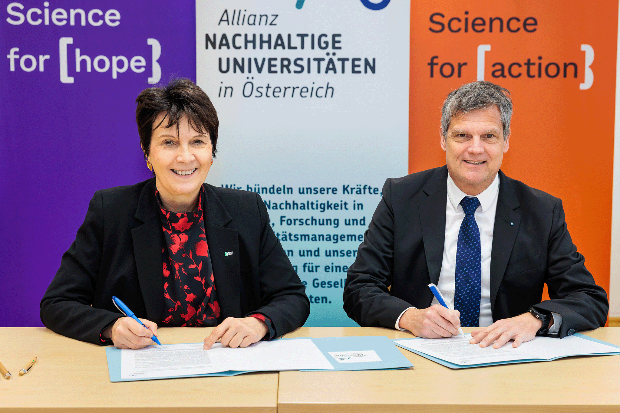 Zwei sitzende Personen, die dabei sind einen Vertrag zu unterzeichnen.