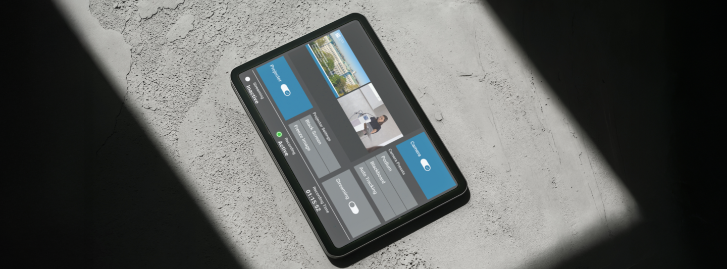Tablet with a touchscreen user interface for lecture hall control, placed on a concrete floor with shadows