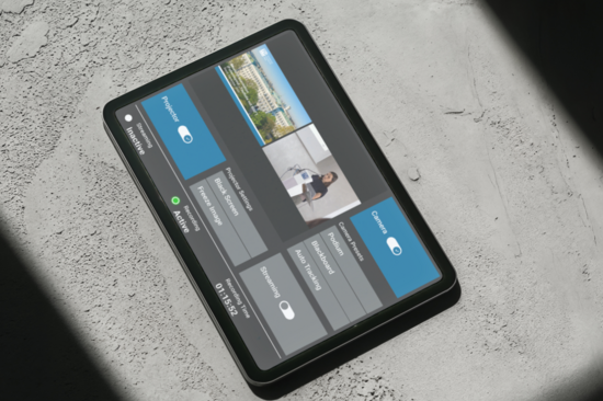 Tablet with a touchscreen user interface for lecture hall control, placed on a concrete floor with shadows