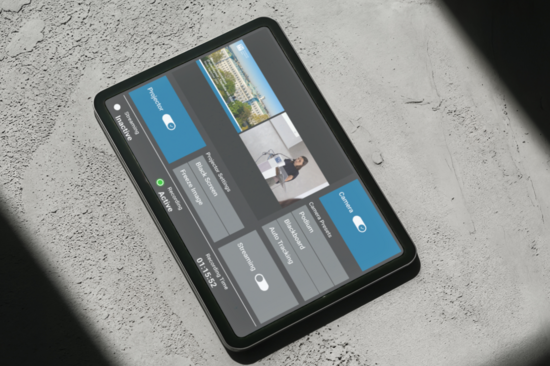 Tablet with a touchscreen user interface for lecture hall control, placed on a concrete floor with shadows