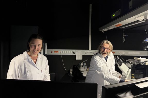 zwei Personen im Laborkittel in einem dunklen Raum