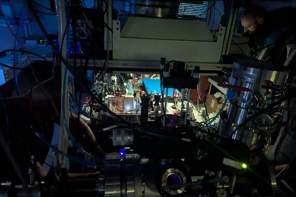 A dimly lit laboratory, with a person working at the optical bench