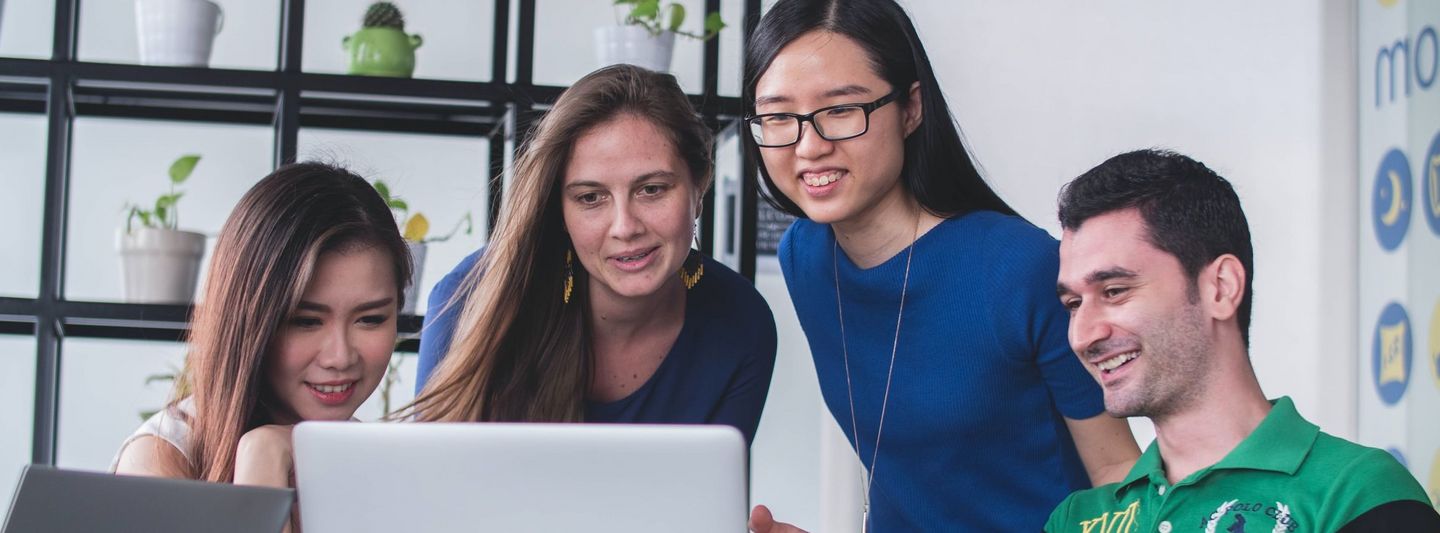 Students consult in front of a laptop