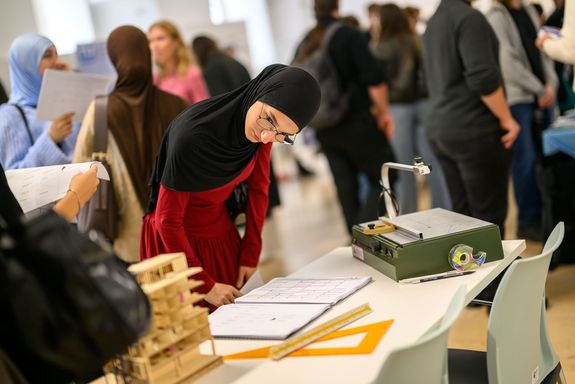 Studierende bei Stand mit Blick auf Unterlagen