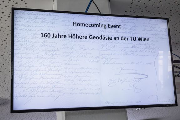 Bildschirm, Hintergrund weiß, Schrift dunkelblau "Homecoming Event 160 Jahre Höhere Geodäsie an der TU Wien"