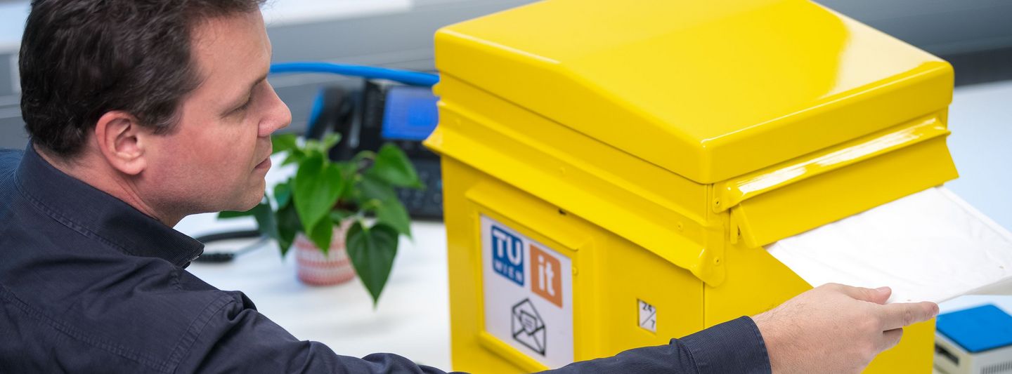 Mann wirft Post in einen Postkasten