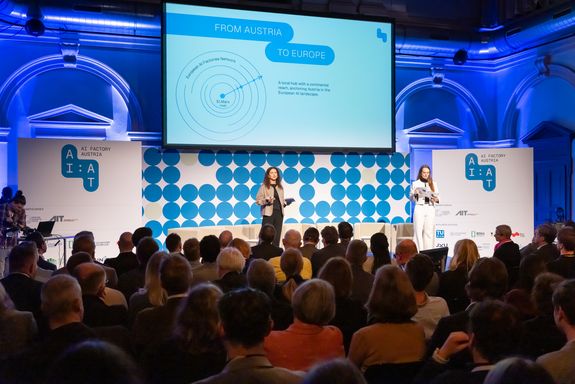 Voller Saal, zwei Frauen auf der Bühne.