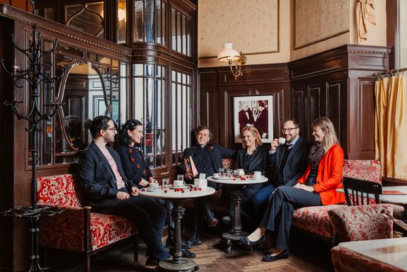 Gruppenfoto Menschen sitzend in Kaffeehaus