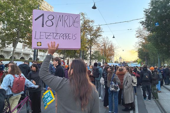 Menschenmenge; Mann von hinten sichtbar hebt Schild nach oben auf dem steht: 18 Mrd. € Letzte Preis.
