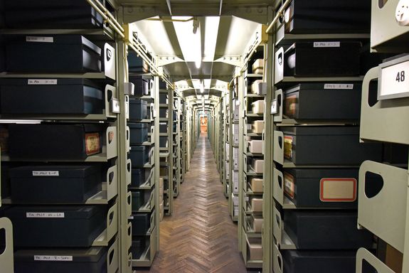 Blick ins Archiv: langer Gang mit Regalen und Aktenordnern