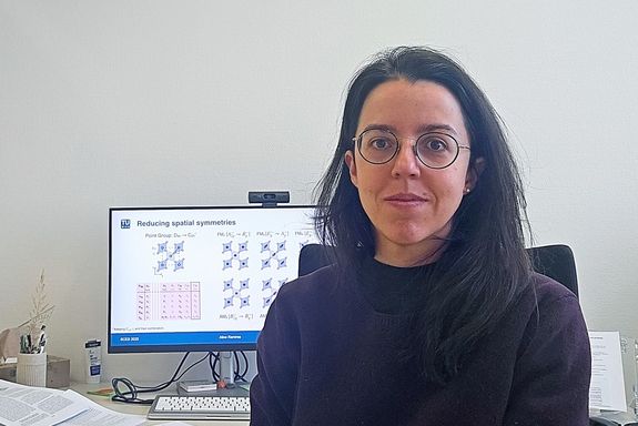 Aline Ramires am Schreibtisch, im Hintergrund ein Desktop