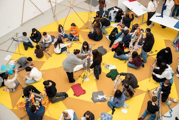 gelber Teppich, darauf Kinder, die Arbeiten, von oben fotografiert